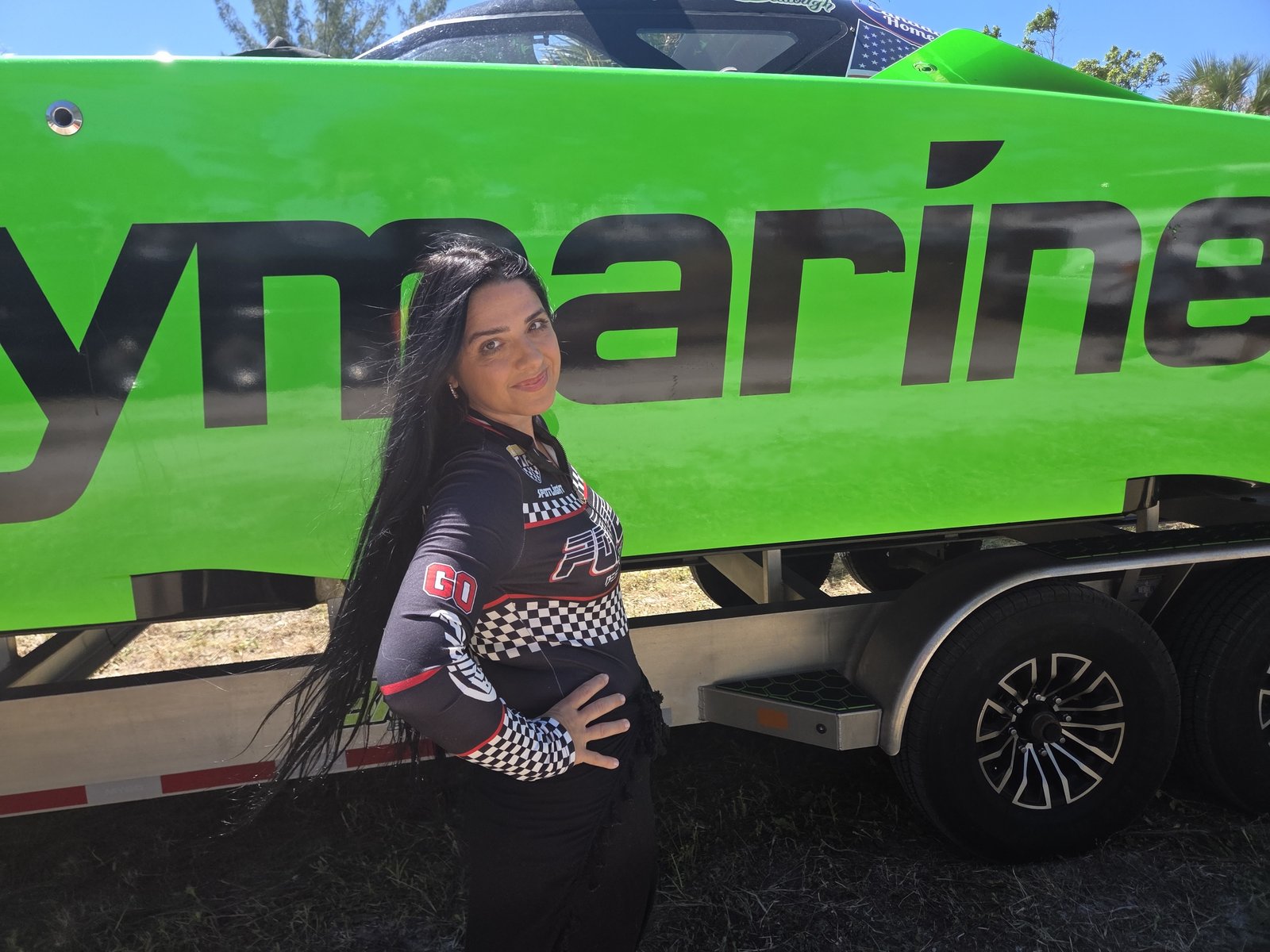 Posing beside a green race catamaran on its trailer
