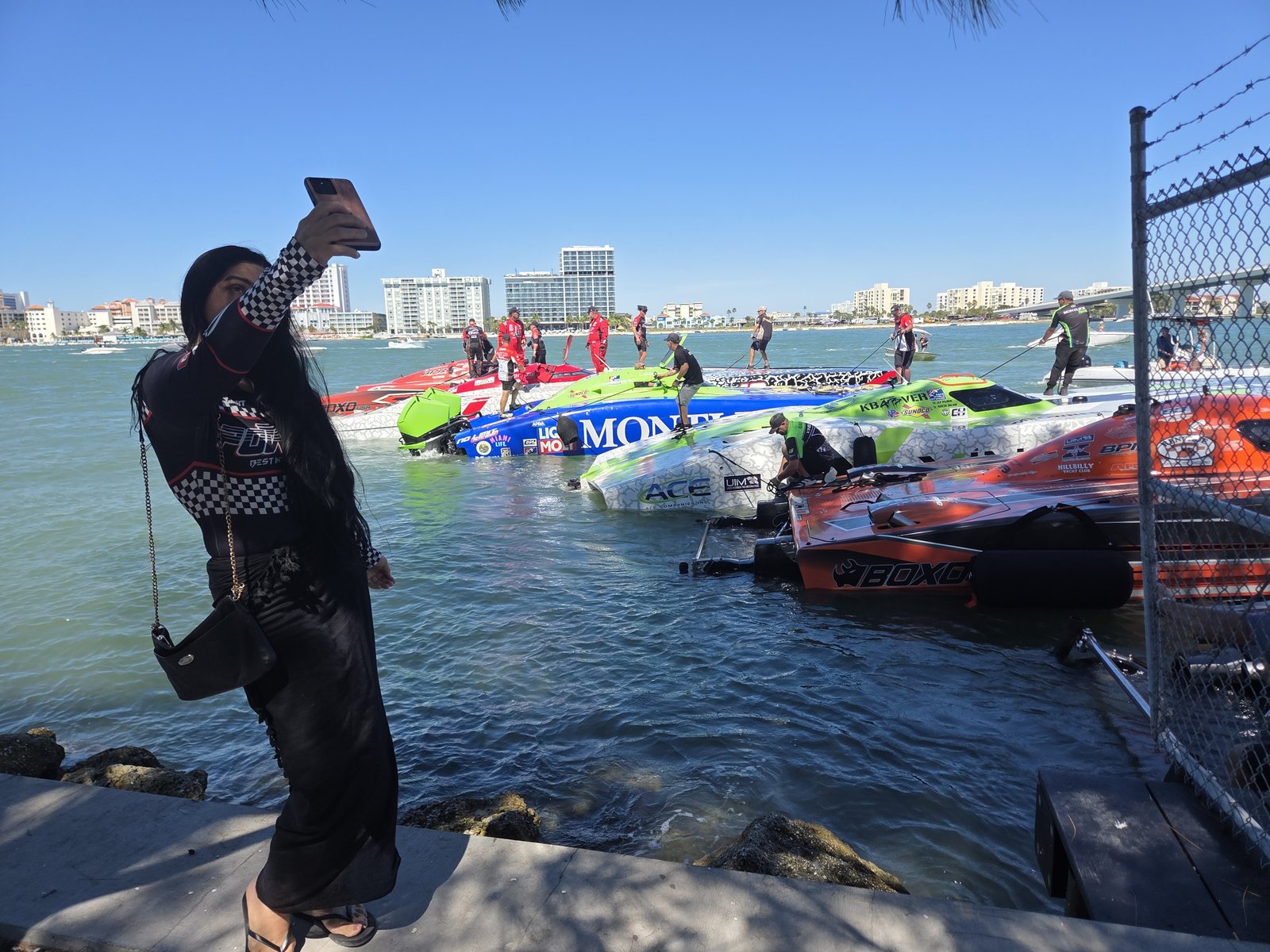 Spectator photographing the line of race boats from the rocks