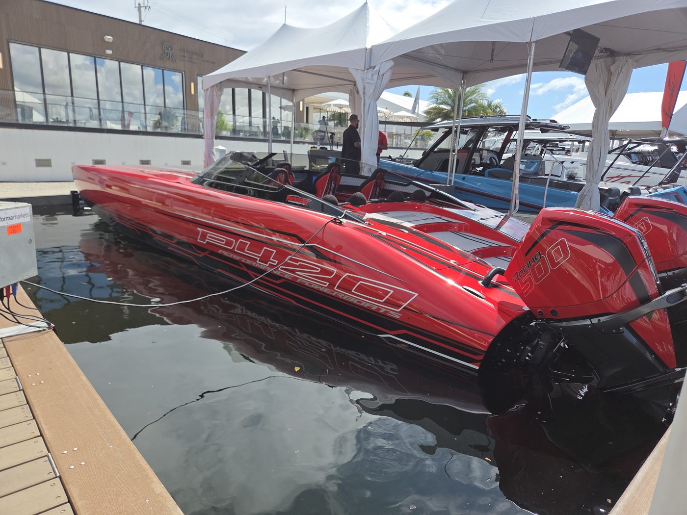 Red performance catamaran with twin outboards under a white tent