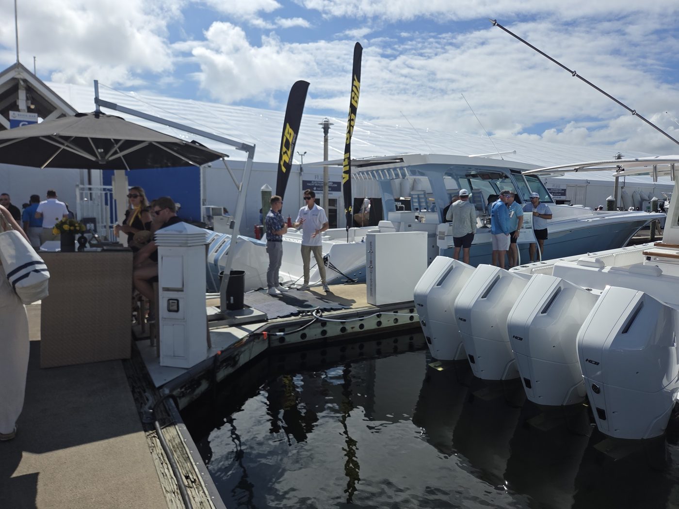 Row of four white outboards on a boat beside a dockside bar at FLIBS 2026