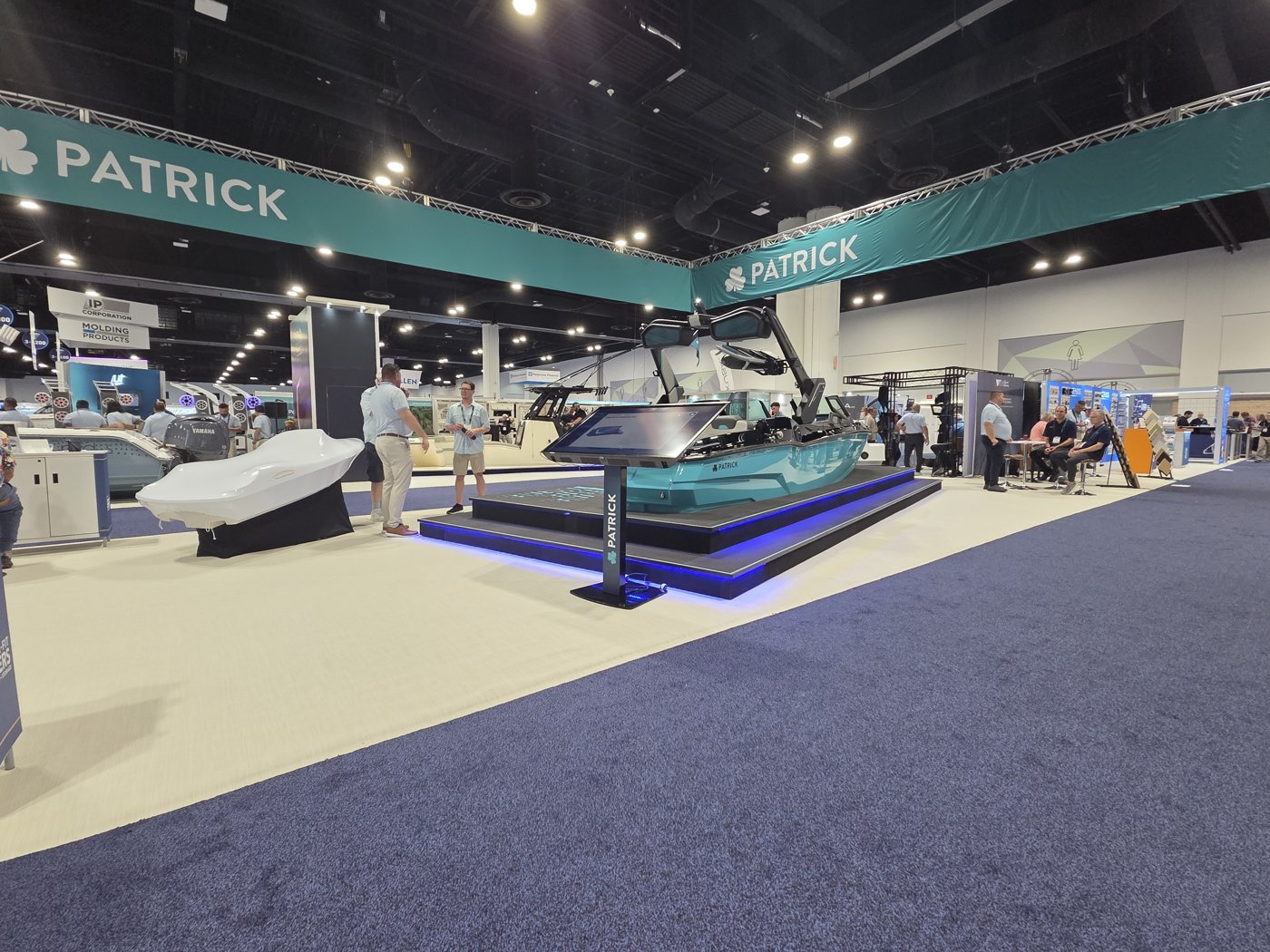 Patrick booth with a teal wake boat on a blue-lit platform and a touchscreen kiosk