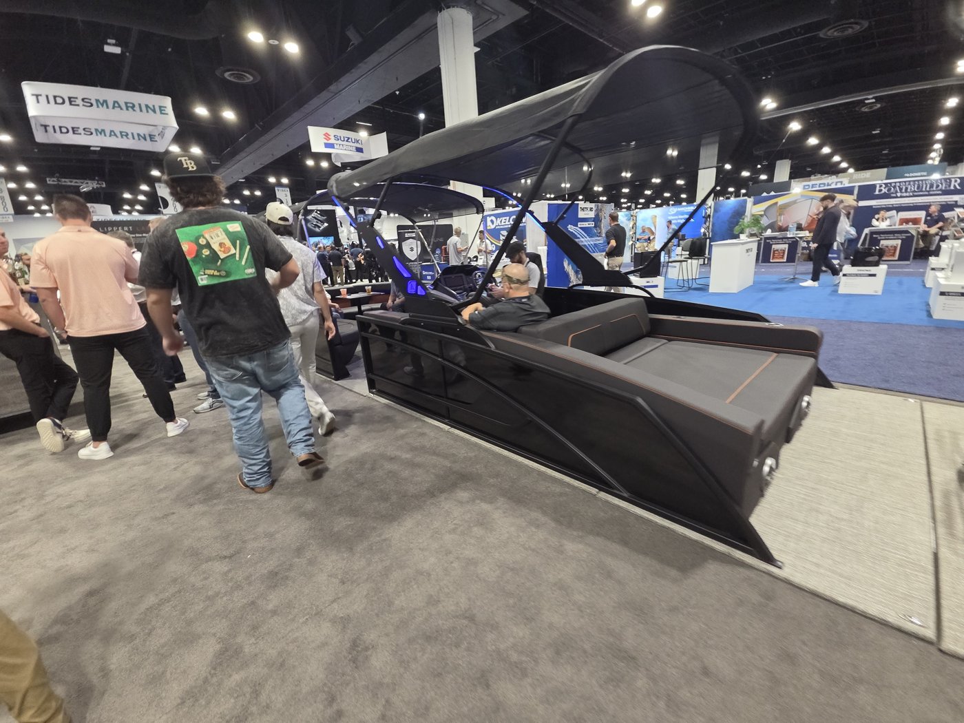 Side view of the black pontoon with Tides Marine, Suzuki Marine, Kelcom and Lippert signs